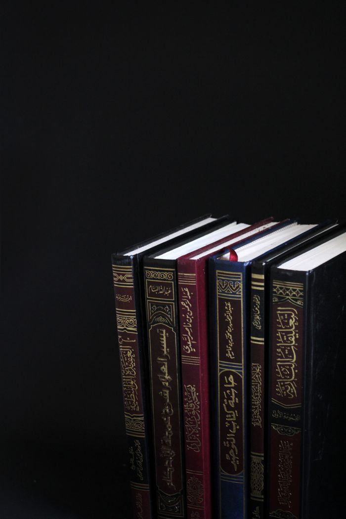 A collection of Arabic books arranged vertically on a black background.